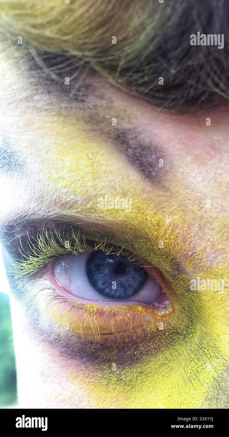 Occhio blu con vernice in polvere gialla sulle ciglia Foto Stock