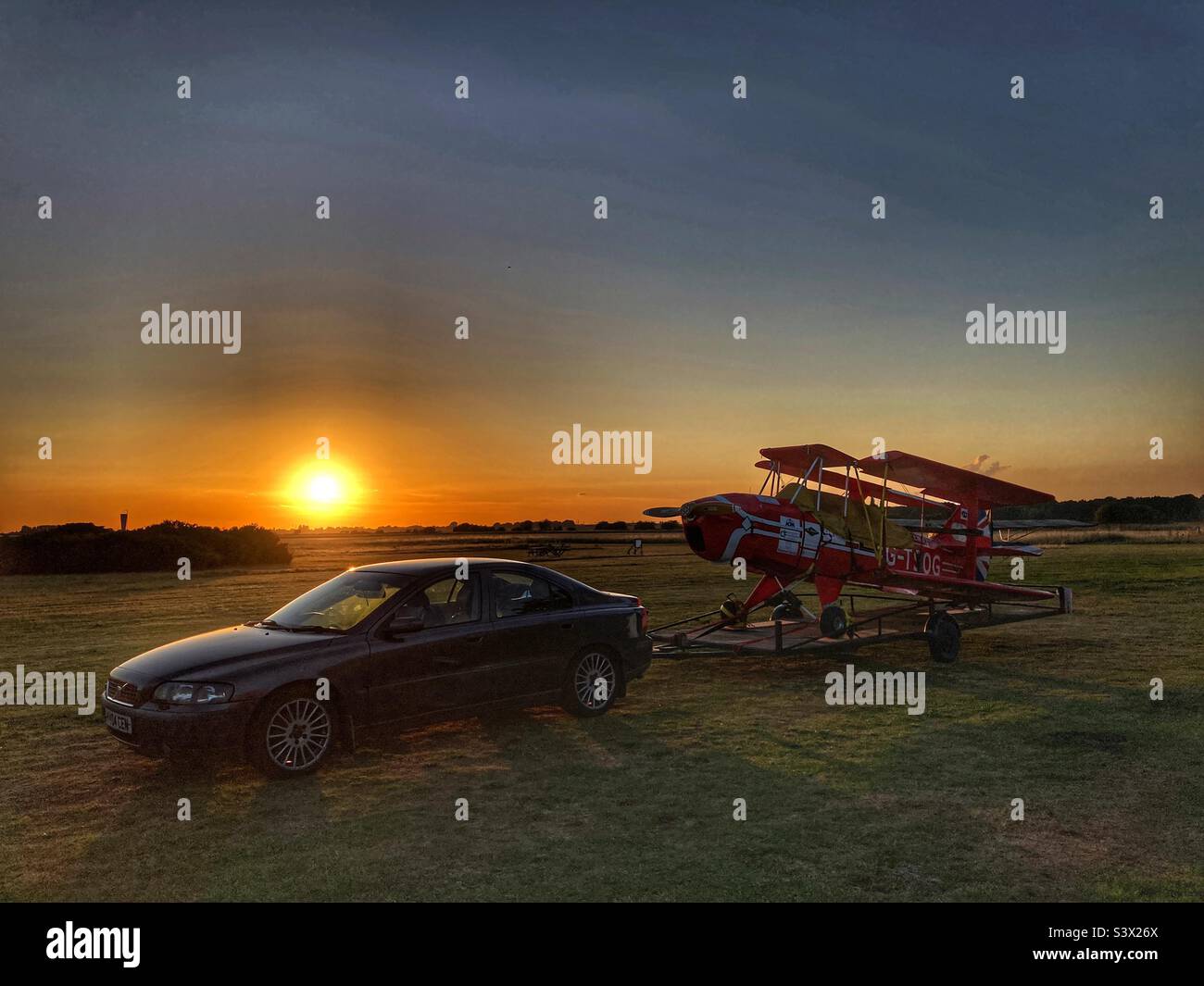 Auto Volvo con un biplano Sherwood Ranger su un rimorchio al tramonto. - Immagine stock catturata con smartphone
