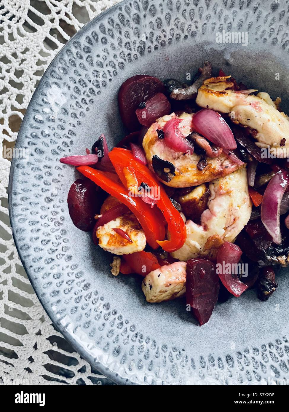 La bontà in una ciotola. Halloumi fritti in padella con pepe rosso, cipolla rossa, barbabietola e funghi. Foto Stock