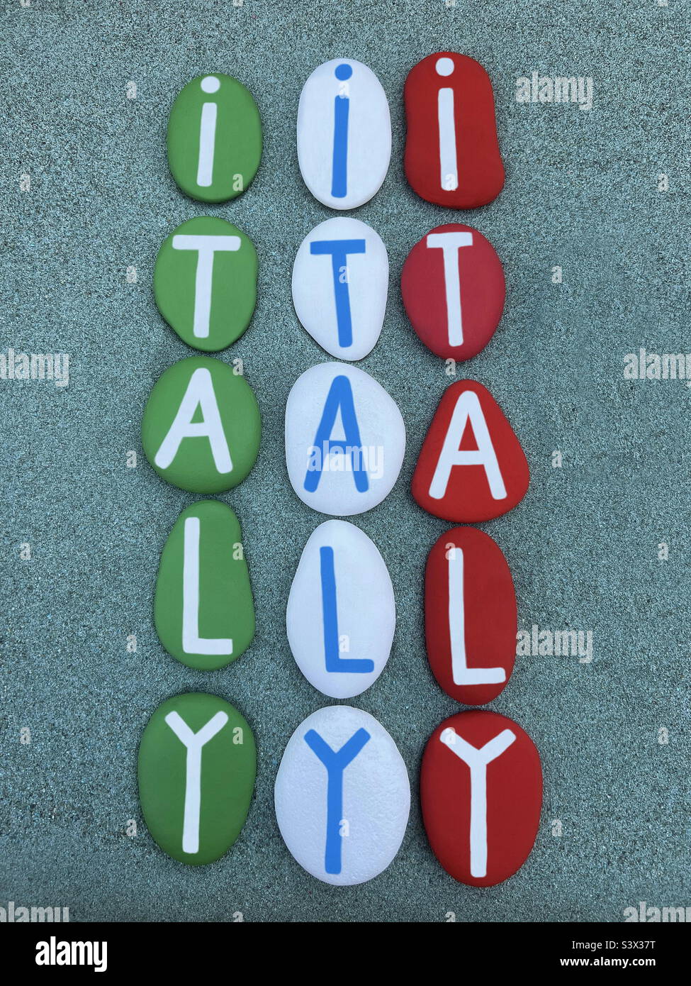Italia, souvenir unico composto da lettere di pietra dipinte a mano verde, bianco e rosso su sabbia verde - Immagine stock catturata con smartphone