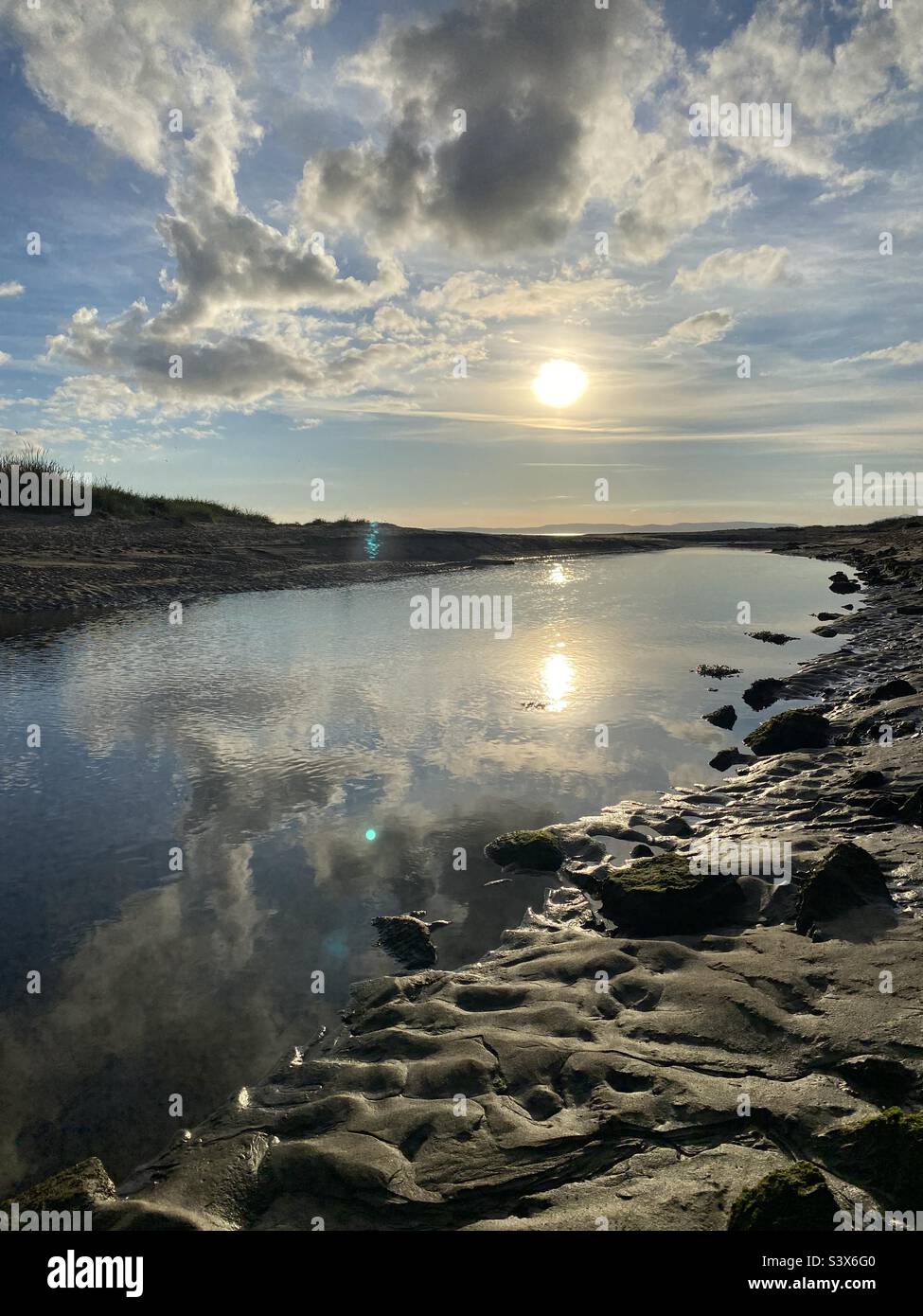 Sole e nuvole riflessi in un fiume Foto Stock