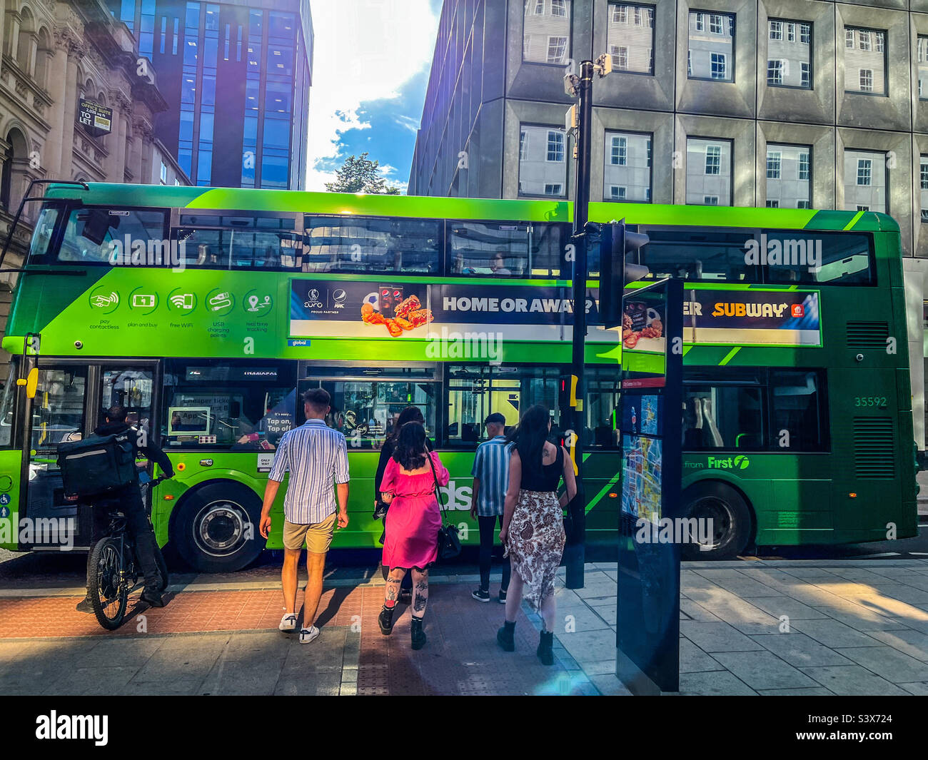 Persone in attesa di attraversare la strada a Leeds mentre l'autobus passa Foto Stock