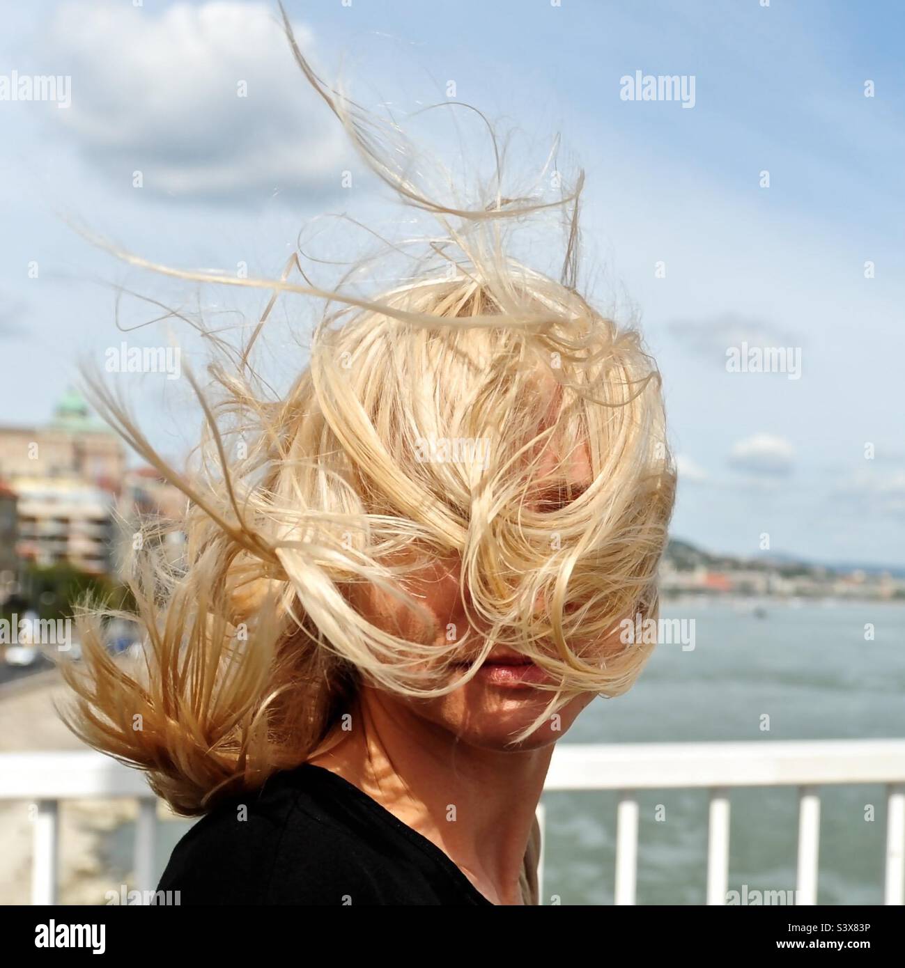 Ragazza nel ponte con i capelli biondi ventosi durante le calde giornate di sole Foto Stock