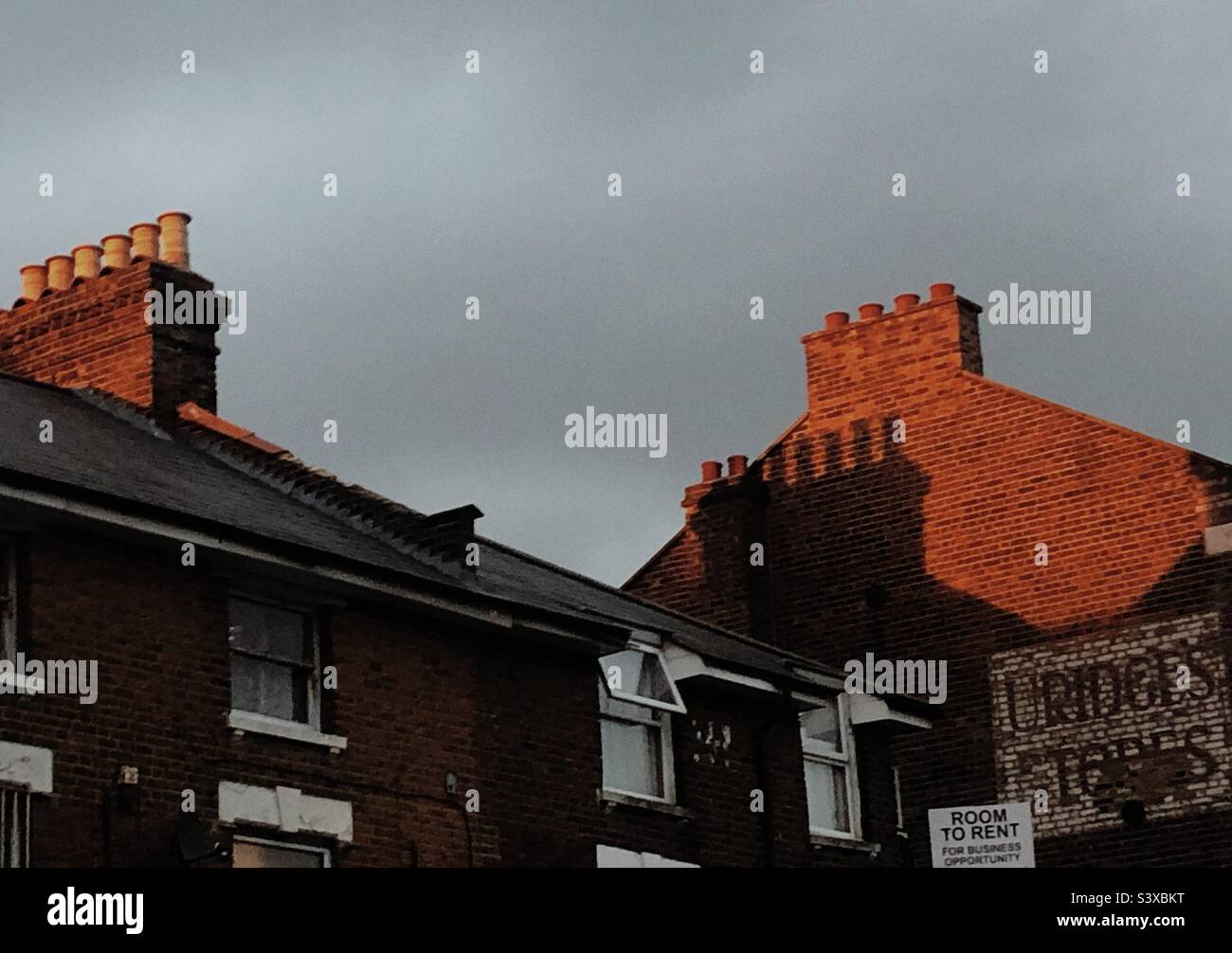 Lato di un edificio a muro in mattoni alla luce della sera contro un cielo sovrastante in Bromley Londra Inghilterra - Immagine stock catturata con smartphone
