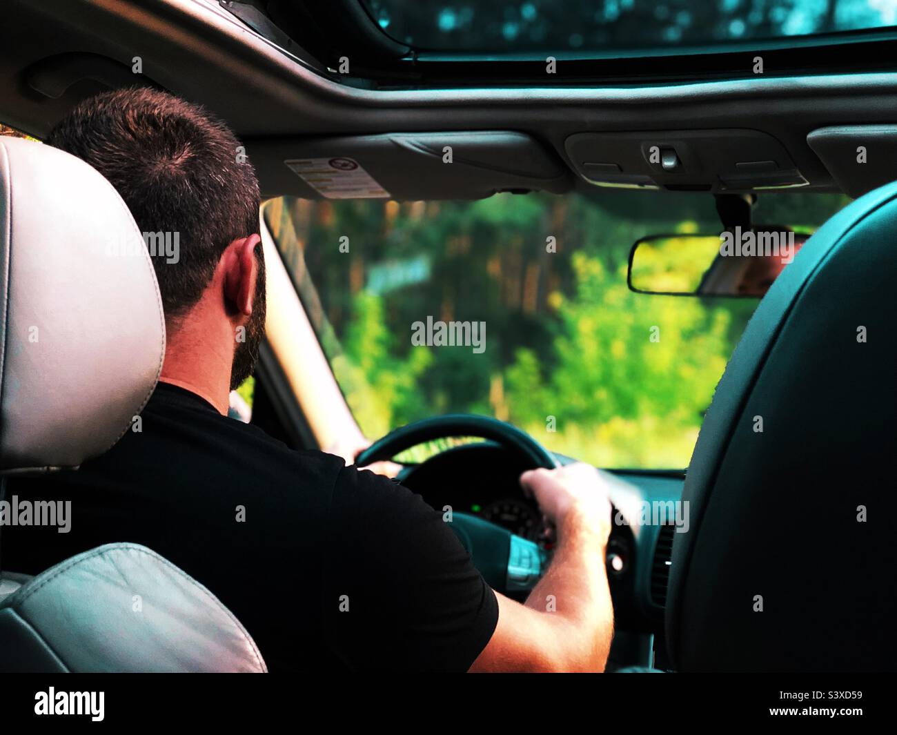 Giovane uomo che guida un'auto attraverso la strada forestale Foto Stock