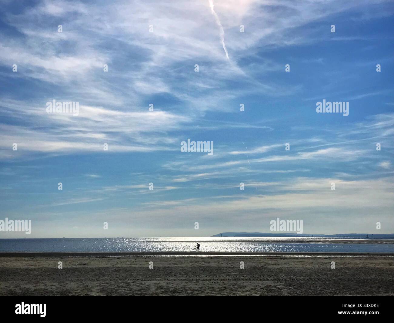 Ciclista sulla spiaggia di West Wittering, West Sussex, Regno Unito Foto Stock