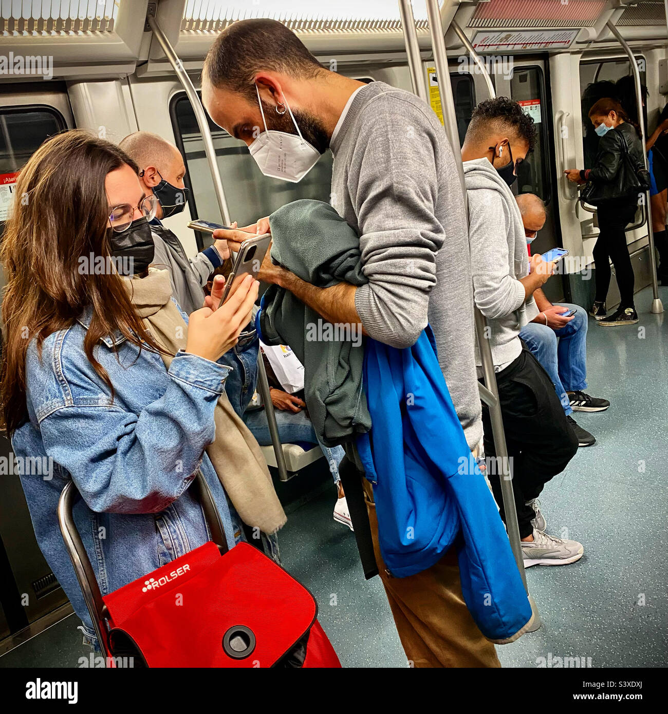 Pendolari e turisti durante i viaggi covid sulla metropolitana di Barcellona scorrendo sui loro schermi e perso in concentrazione Foto Stock