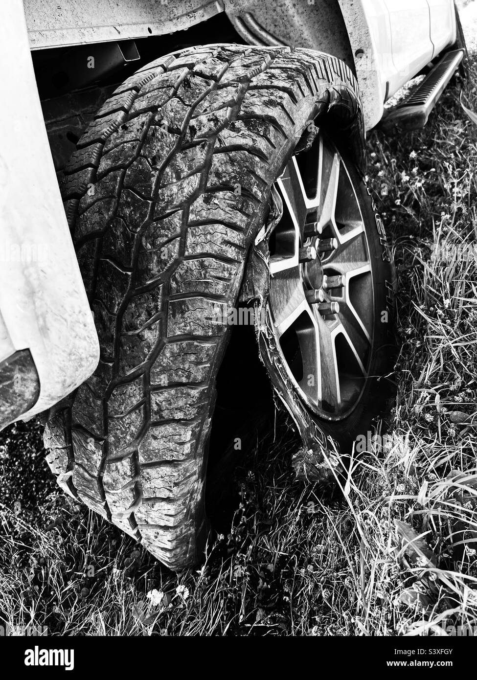 Una foto in bianco e nero dello pneumatico posteriore bruciato su un pick-up bianco. Foto Stock
