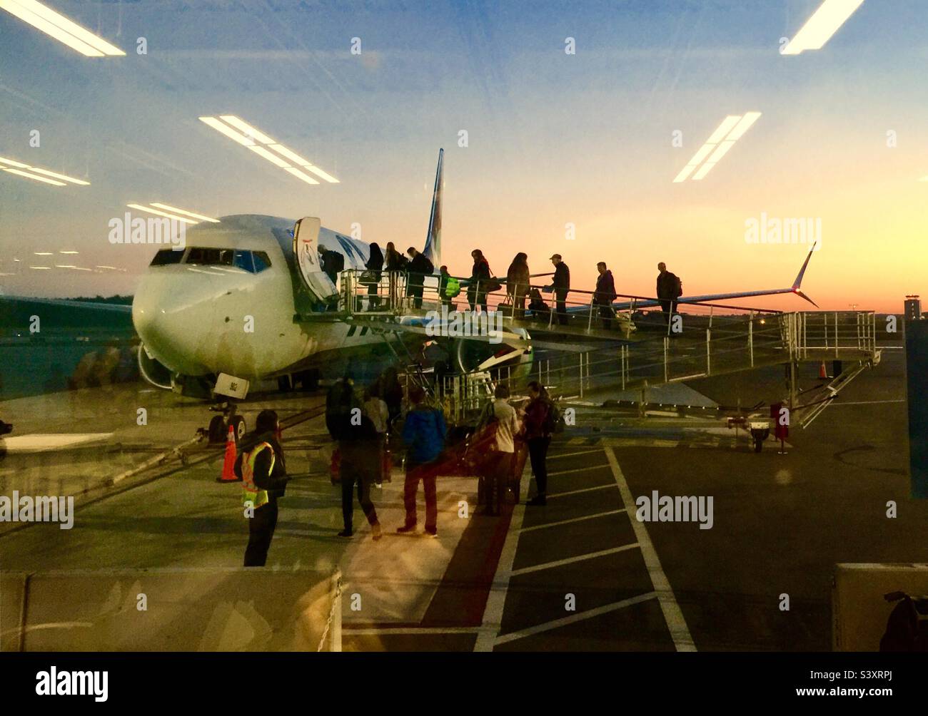 Imbarco su un aereo all'alba. Visto dall'interno del cancello di partenza. Nuovo giorno. Un altro volo. Viaggi aerei. Asfalto. Ecco qui. Vai. Guardando fuori. Foto Stock