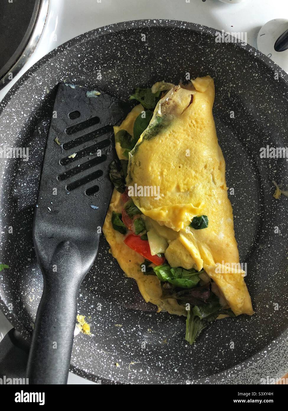 Frittata fatta in casa in padella con formaggio, pomodoro e foglie di insalata - Immagine stock catturata con smartphone