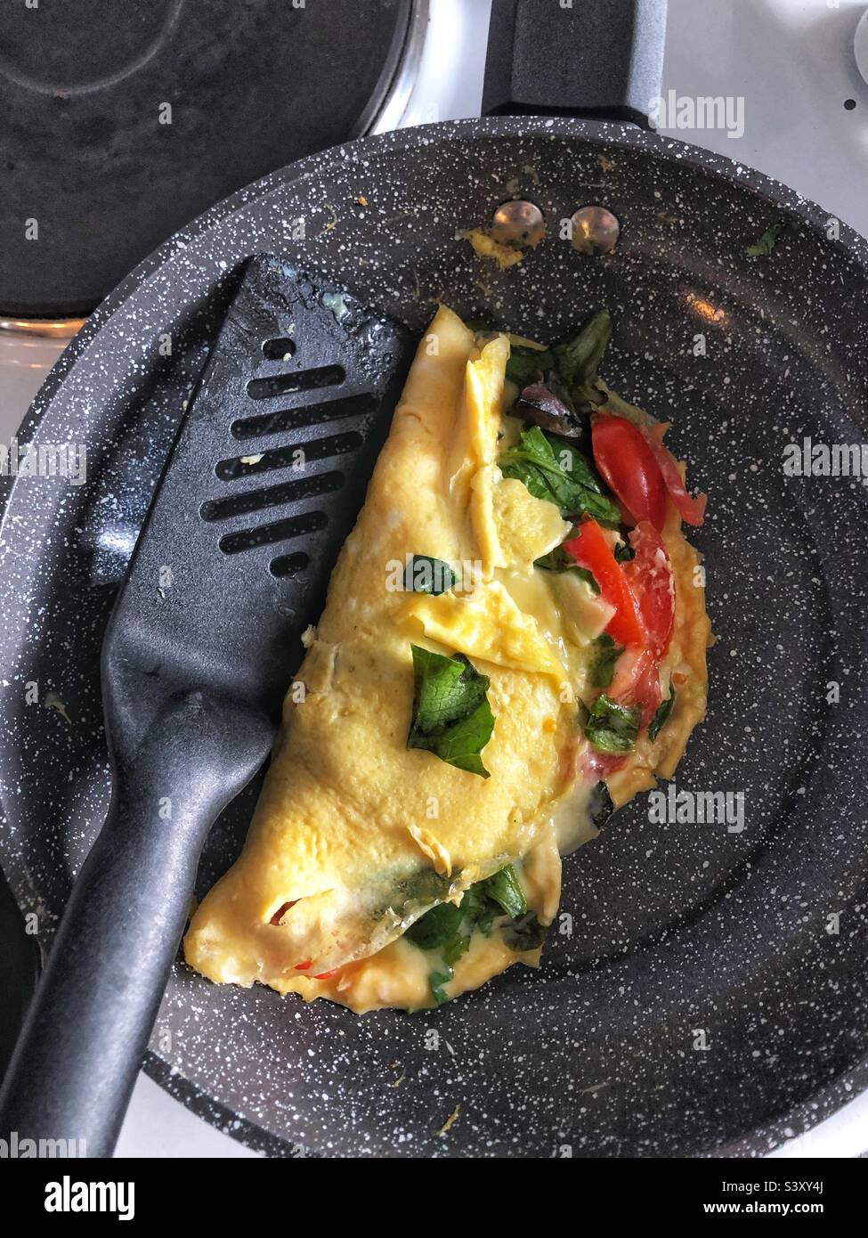Frittata fatta in casa in padella con formaggio, pomodoro e foglie di insalata - Immagine stock catturata con smartphone