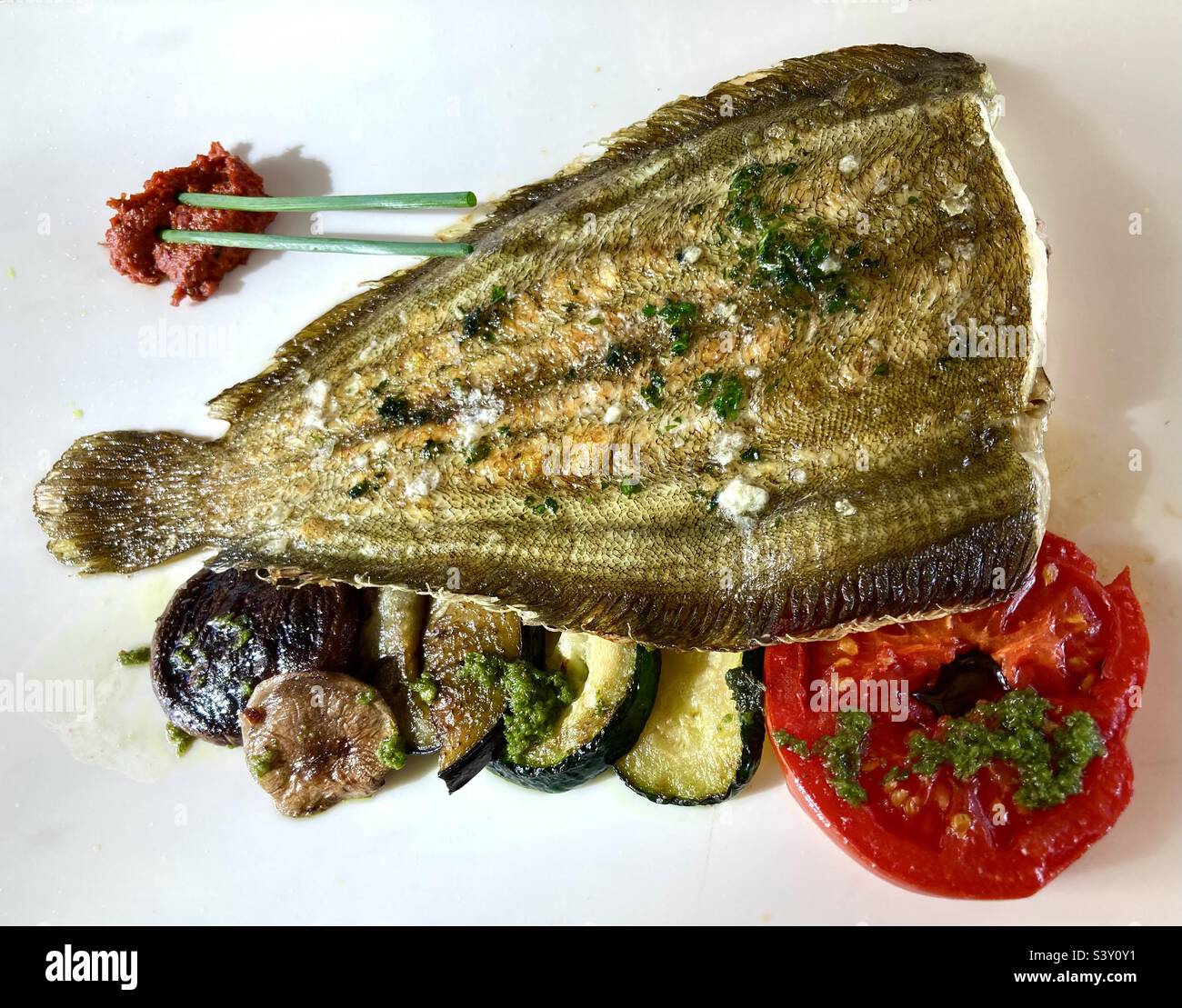 Sogliola al limone con pomodoro e zucchine su piatto bianco - Immagine stock catturata con smartphone
