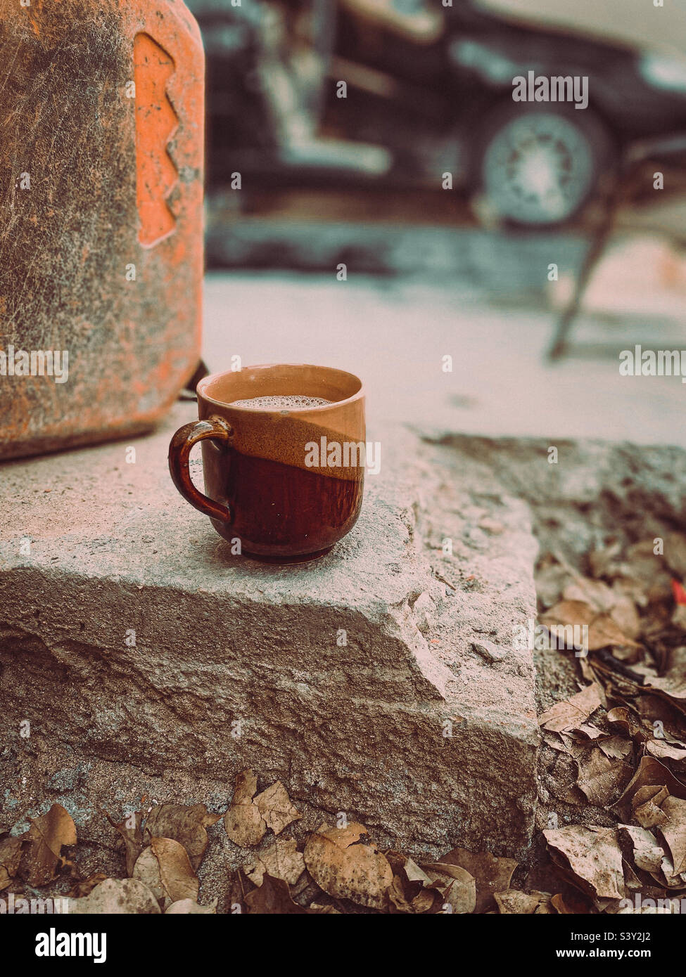 Una tazza da tè messa a terra con un'auto sullo sfondo. Foto Stock