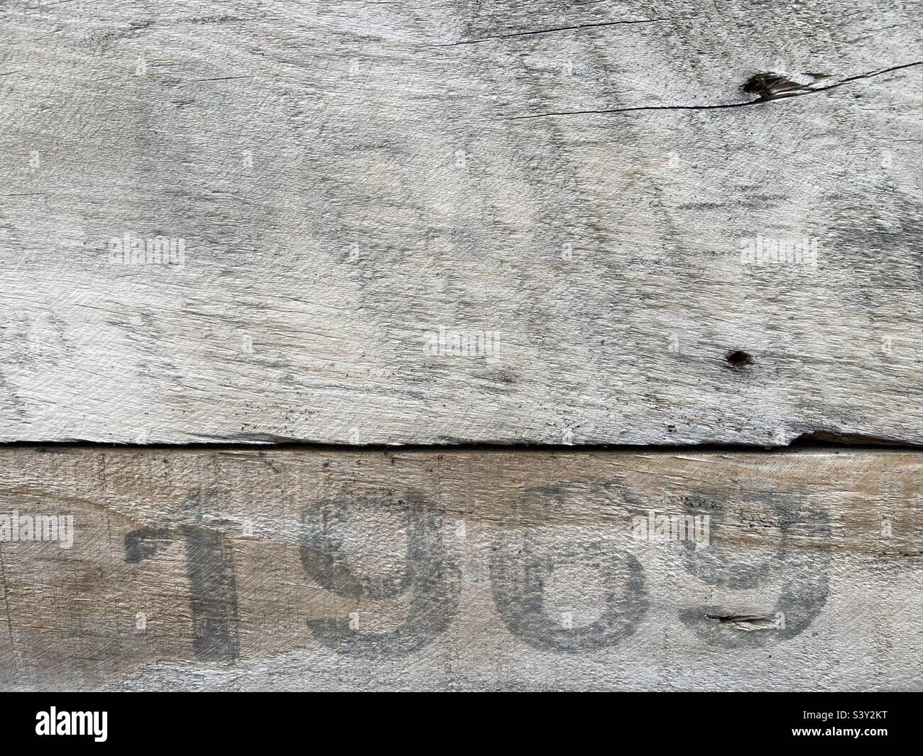 Su un pannello di legno intemperiato è stampato in vernice nera il numero 1969 - Immagine stock catturata con smartphone