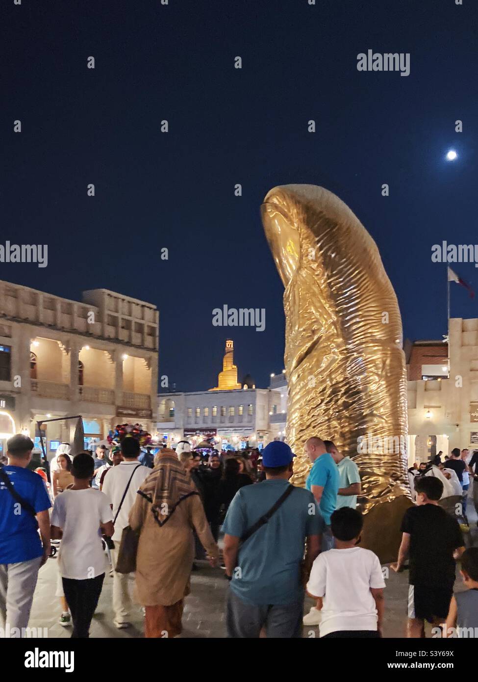La statua del pollice d'oro, Souq Waqif, Doha, Qatar, con il Centro Culturale Islamico del Qatar Fanar sullo sfondo Foto Stock