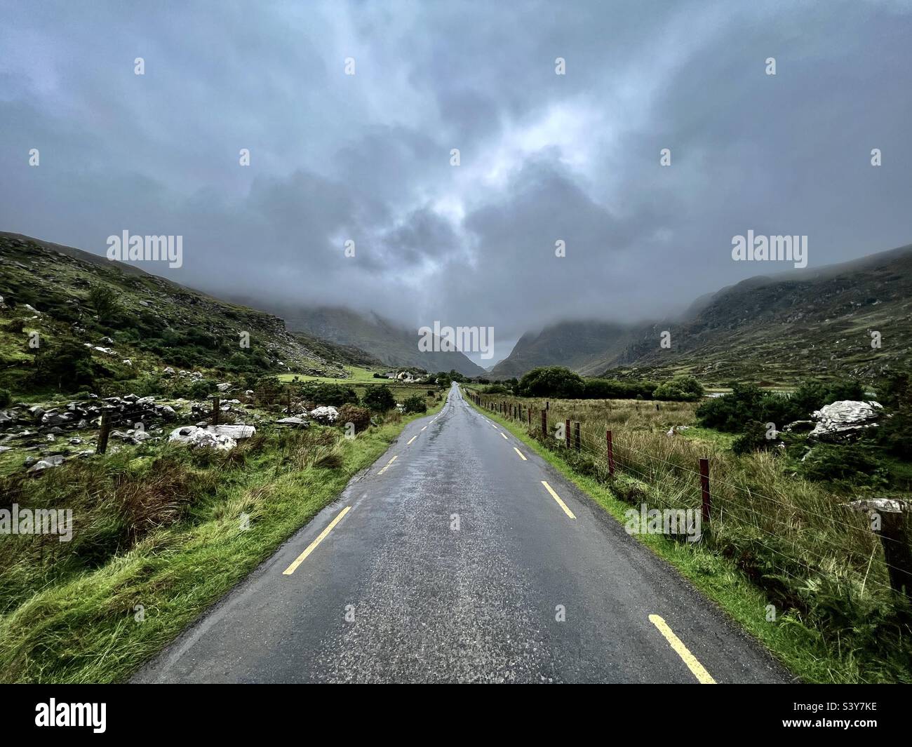 Lunga strada dritta vuota attraverso le colline con campagna su entrambi i lati in Irlanda Foto Stock