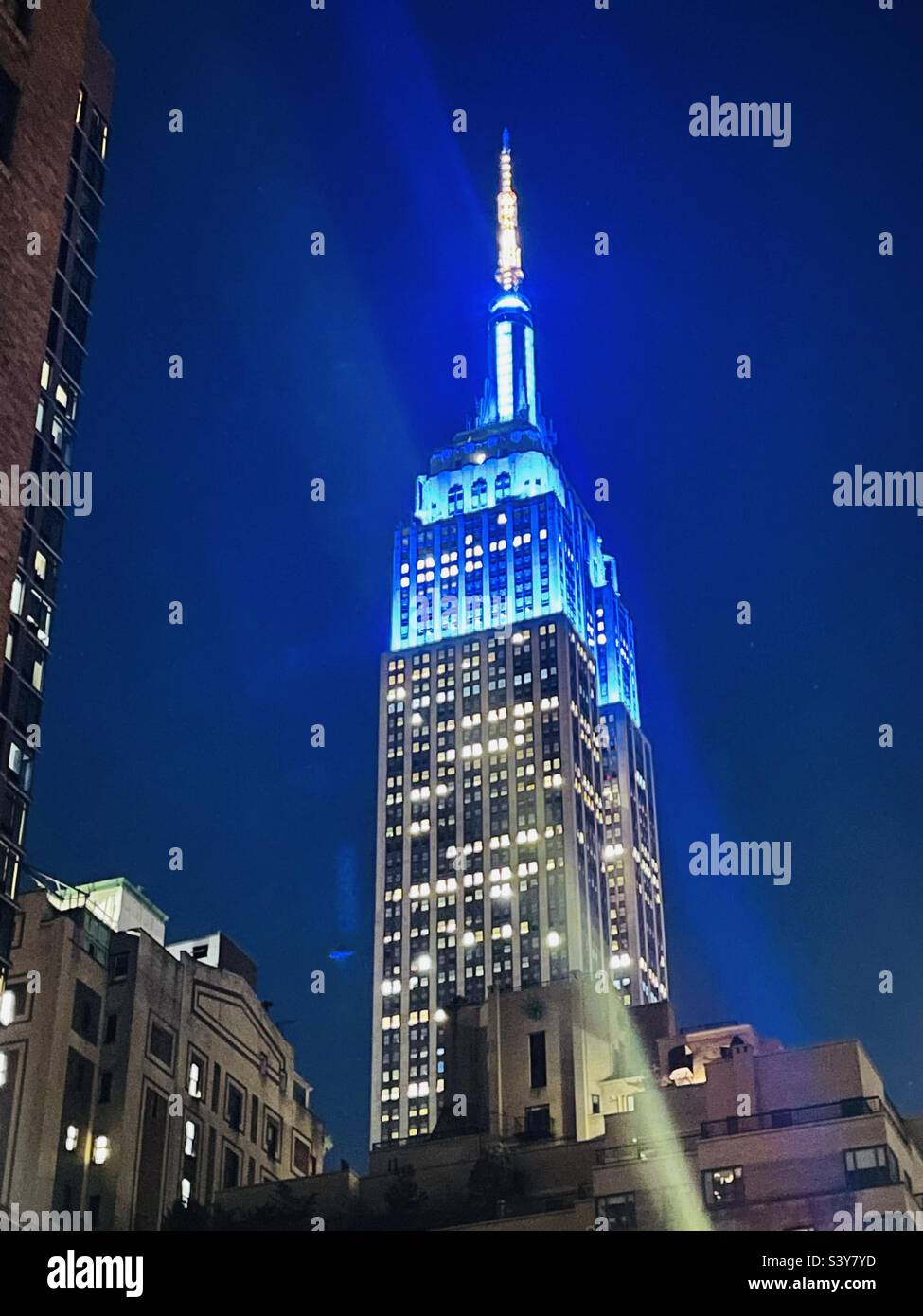 Alcune luci verso l'alto della torre blu sull'Empire state Building di notte Foto Stock