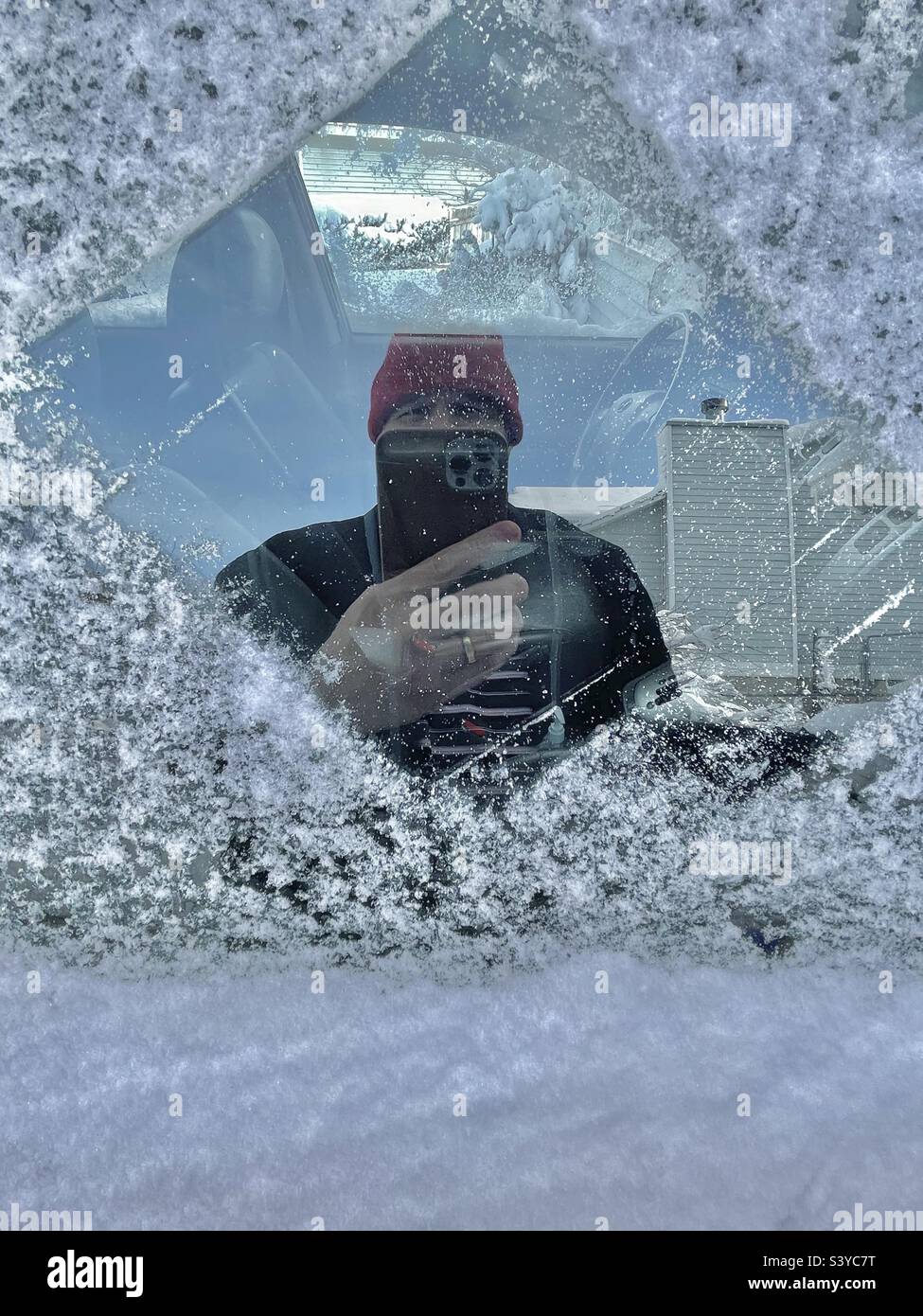 Neve fresca e ghiaccio sono stati raschiati da un finestrino lato passeggero dopo una forte nevicata si è verificata durante la notte in questo quartiere dello Utah, Stati Uniti, con conseguente selfie involontario in vetro riflesso finestra. Foto Stock