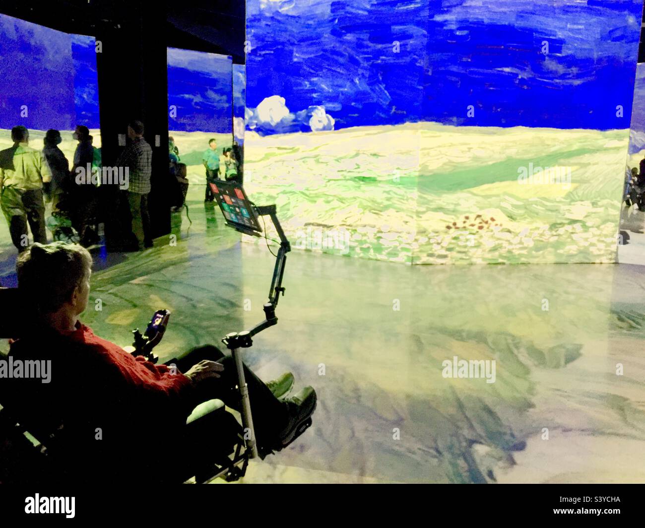 Una persona su una sedia a rotelle motorizzata con schermo in un teatro. Un'unità all'avanguardia con un tablet intelligente. Assistenza alla mobilità. Vedere da vicino. Miracolo della tecnologia moderna. Foto Stock