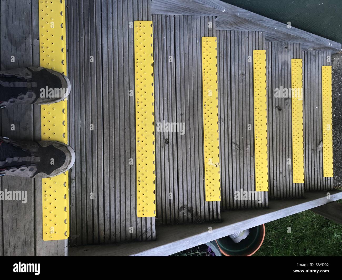 Selfie di due scarpe sulla parte superiore di un volo di sei gradini con bordi gialli per la visibilità dei pericoli. Vista dall'alto che si affaccia sulle scale in discesa. Foto Stock