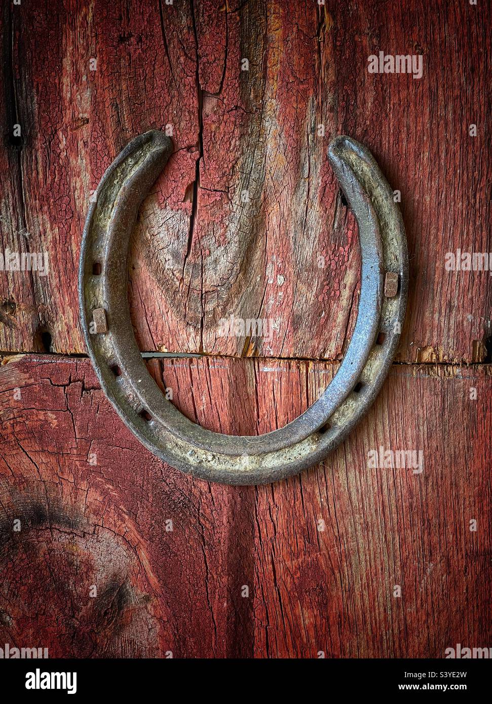 Horseshoe inchiodato ad un posto rosso in un fienile - Immagine stock catturata con smartphone