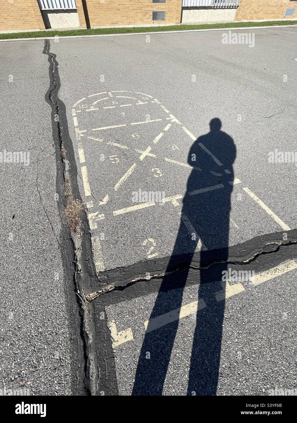 Ombre del passato: L'ex studente visita il vecchio cortile scolastico, ricordando un diagramma di hopscotch familiare sul vecchio asfalto cracked. Foto Stock