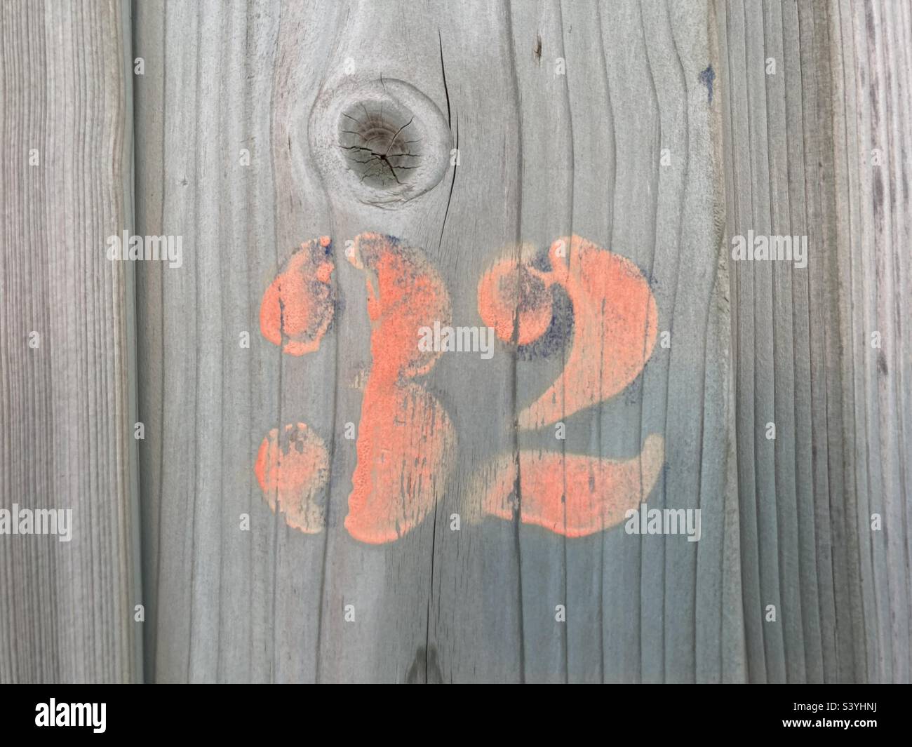 Il numero 32 in colore rosso su legno grigio intemperiato Foto Stock