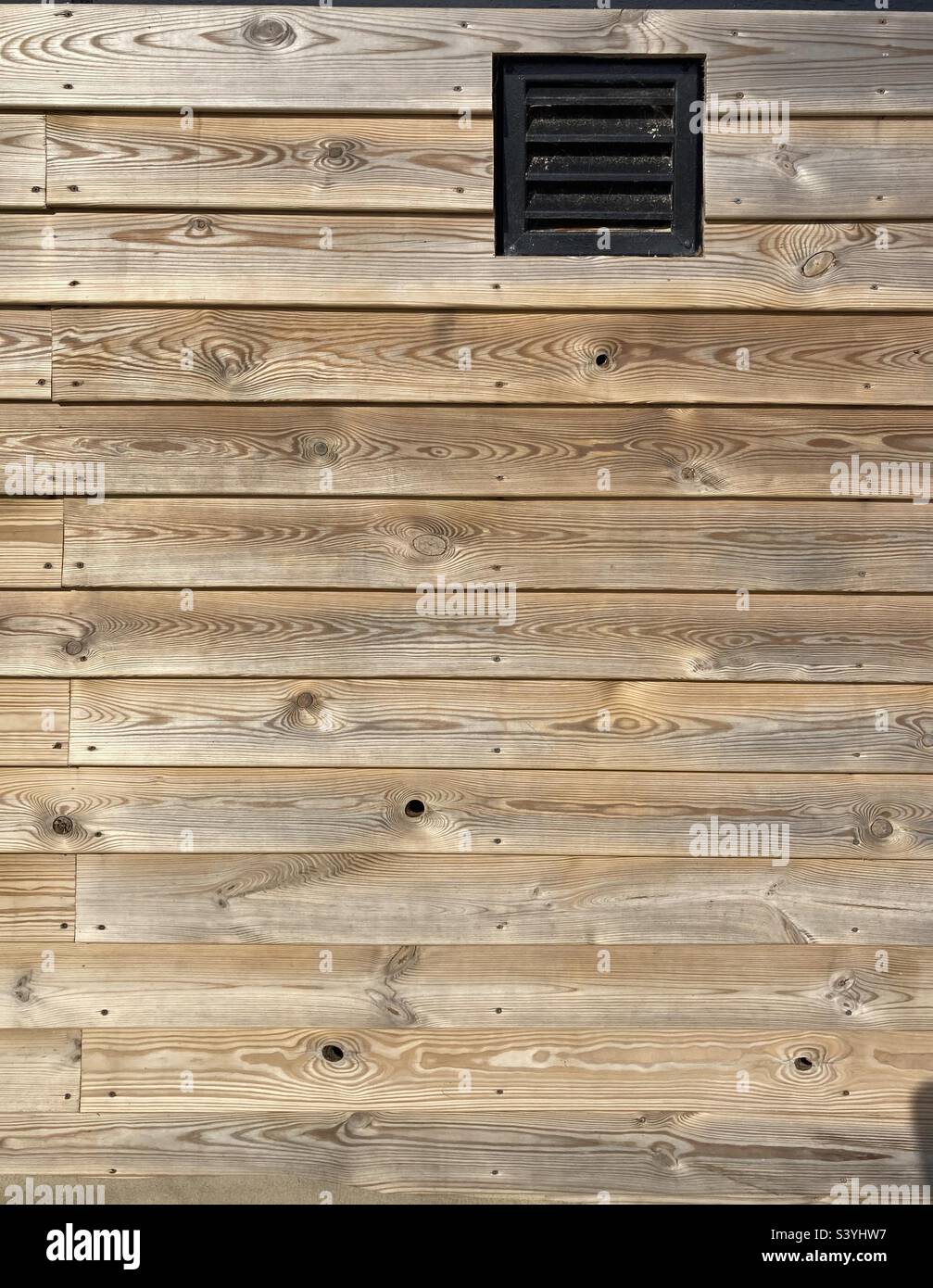 Una parete di legno con griglie di ventilazione quadrate - Immagine stock catturata con smartphone