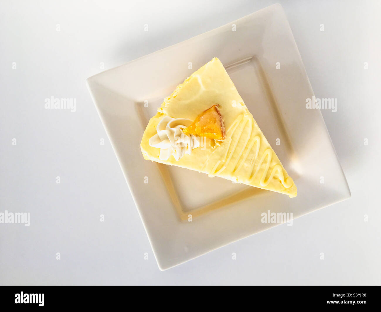 Vista ad angolo elevato di una fetta di mousse fresca e fruttata su un piatto bianco quadrato su sfondo bianco. - Immagine stock catturata con smartphone