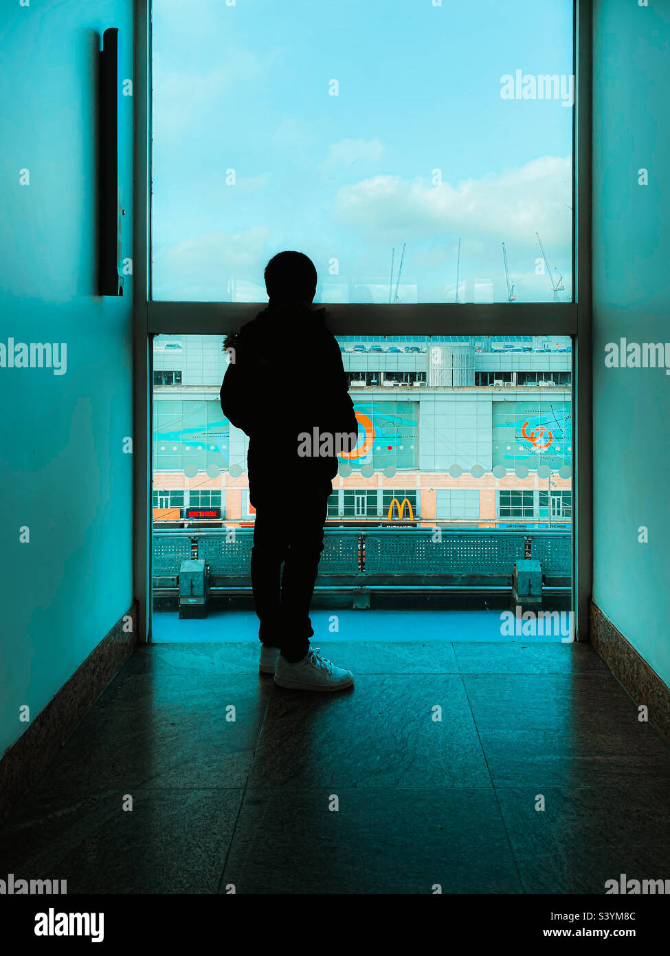 Un ragazzo stava guardando fuori dalla finestra di un alto edificio alla fine di un corridoio Foto Stock