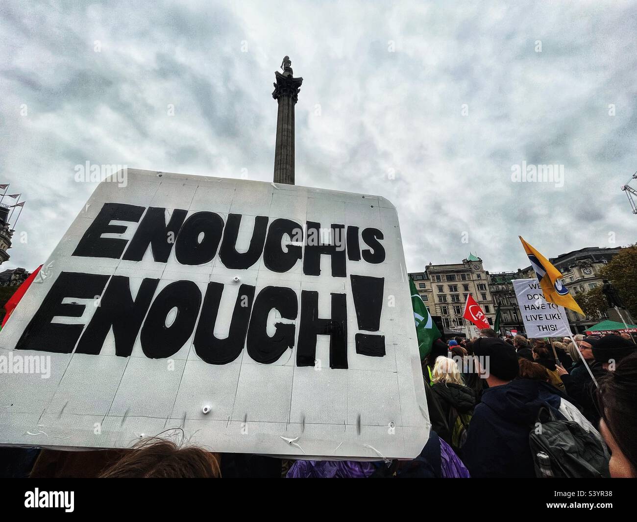 Il cartellone “abbastanza è abbastanza” in risposta ai piani del governo per i tagli del settore pubblico e le politiche di austerità nel quadro britannico di Trafalgar Square con la rubrica di Nelson - Immagine stock catturata con smartphone