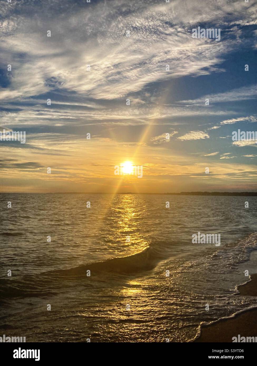 Tramonto sul Long Island Sound con i raggi del sole che esplodono in una bella giornata sulla spiaggia - Immagine stock catturata con smartphone