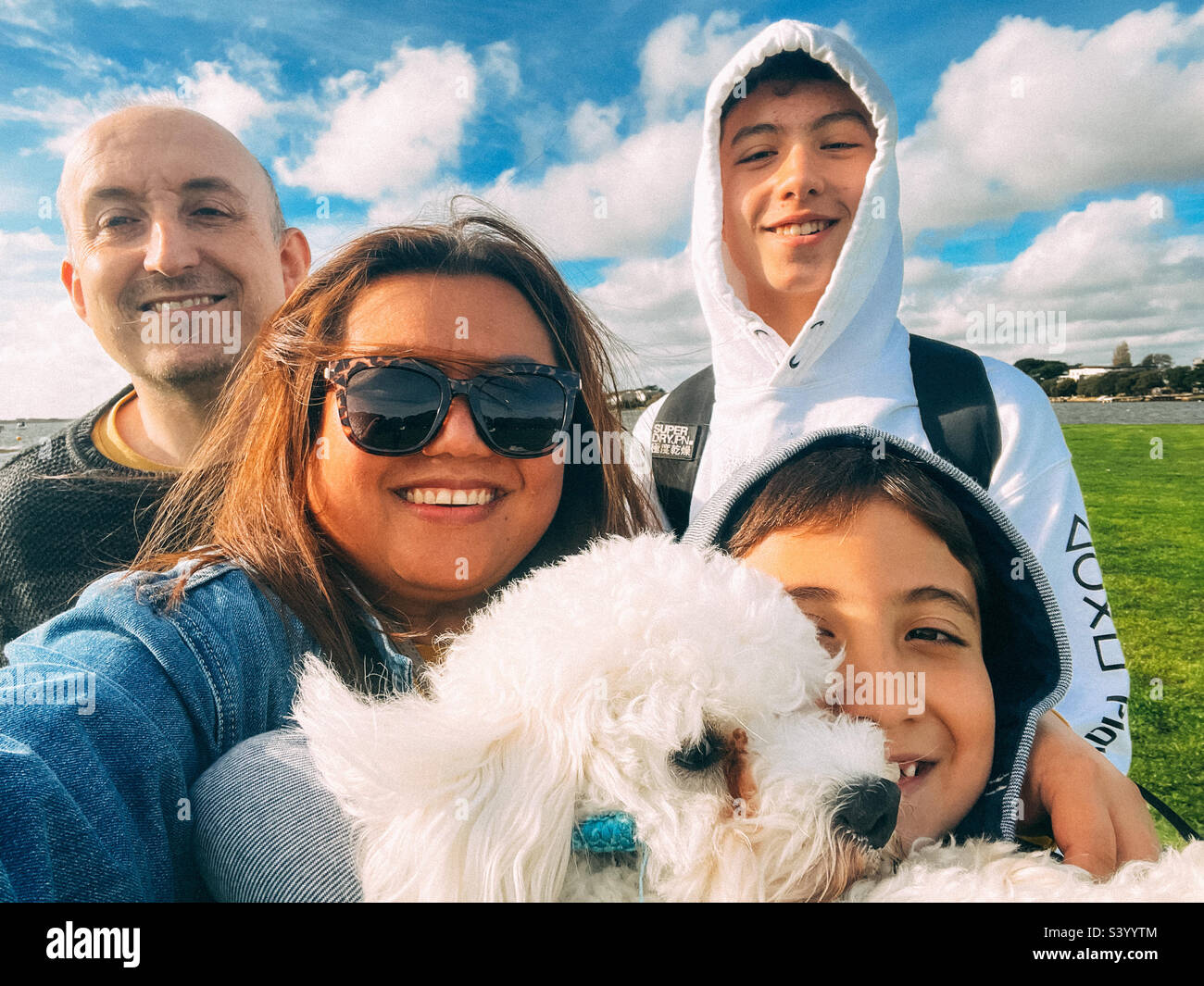 Un ritratto di famiglia con il piccolo cane da compagnia bianco. Foto Stock