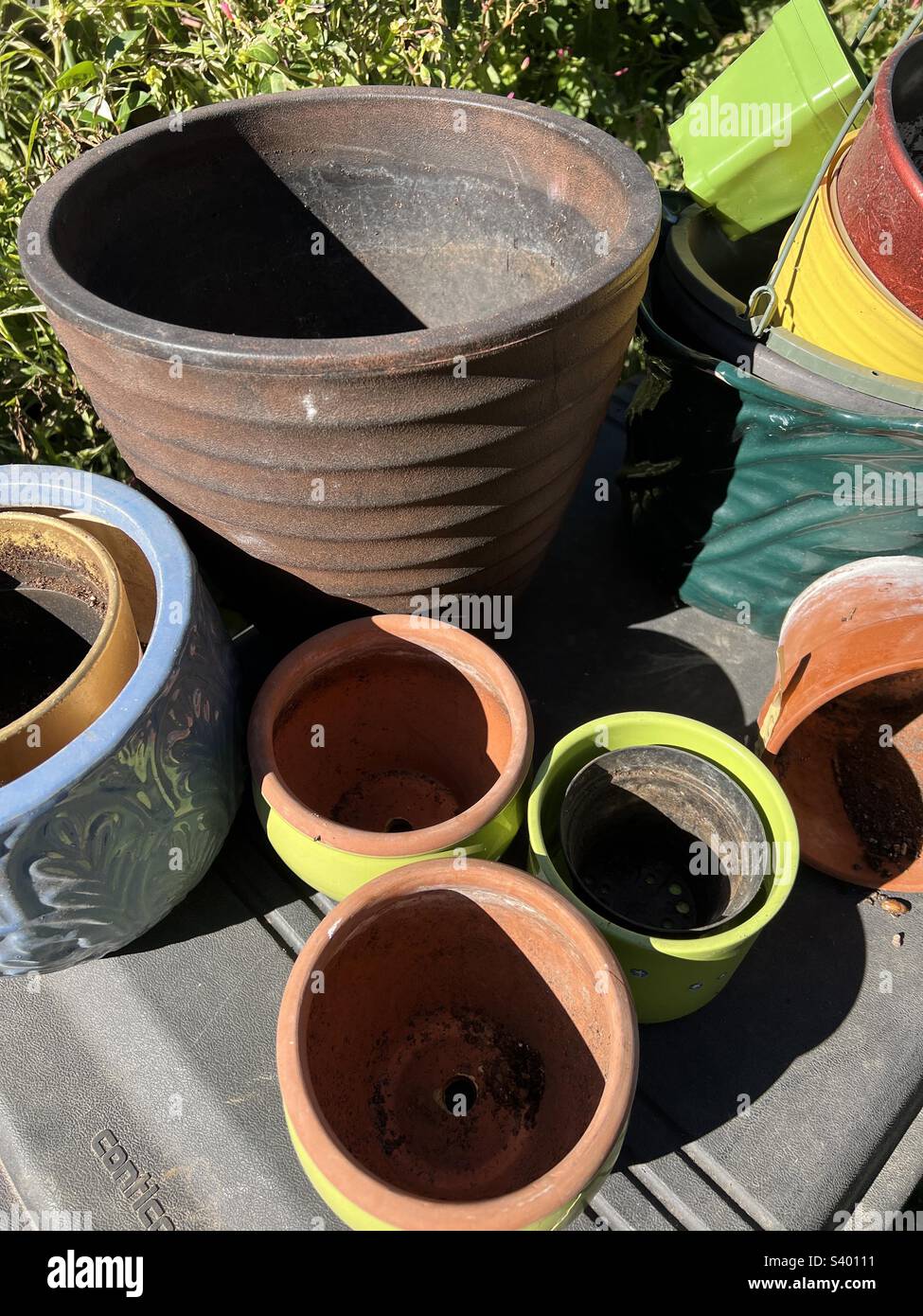 Vasi di fiori di dimensioni casuali in vari colori dal verde all'arancio al blu pronti e in attesa di piantagione primavera Foto Stock