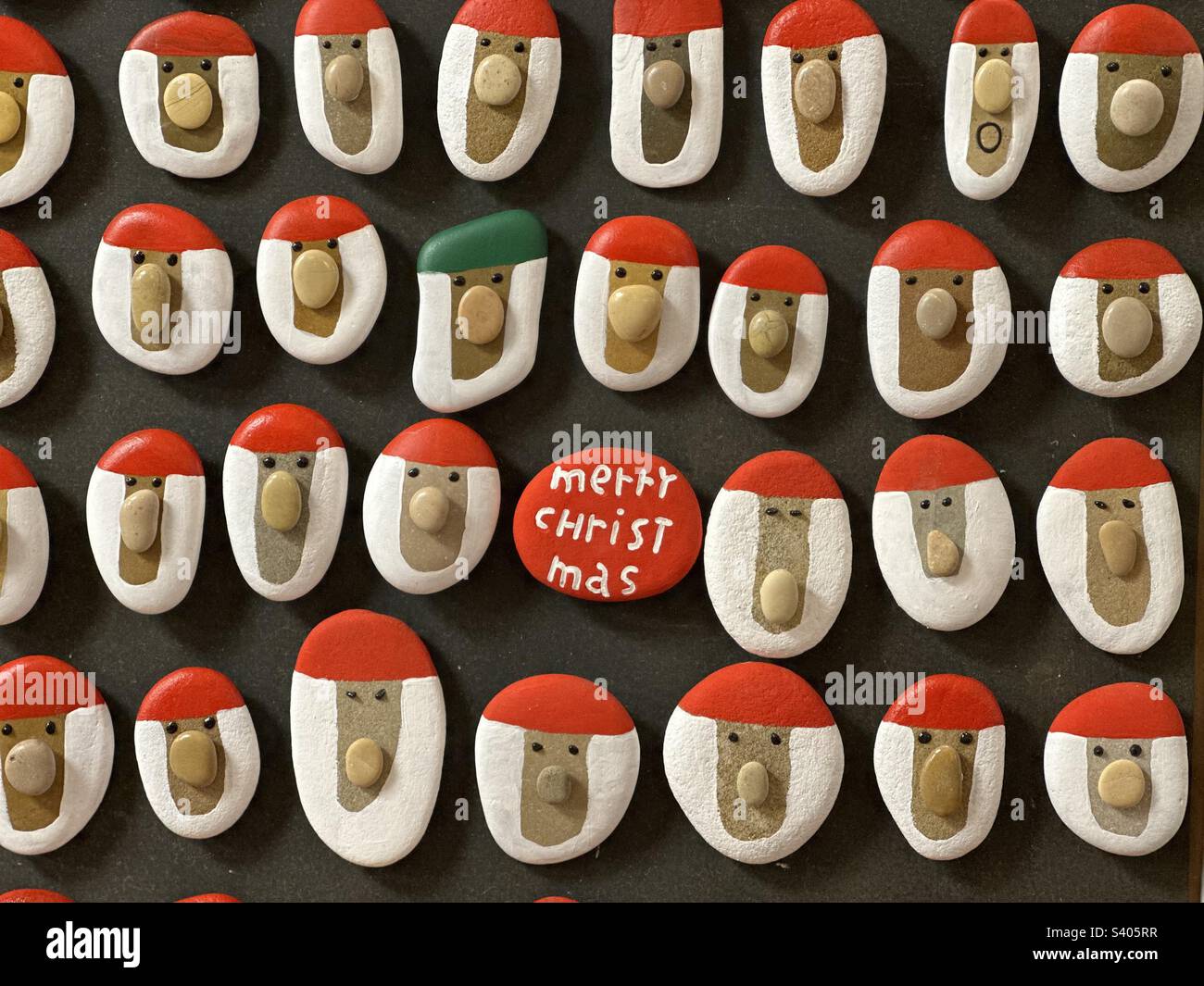 Molti magneti fatti a mano di pietra di Babbo Natale su una tavola di legno al mercato di Natale Foto Stock