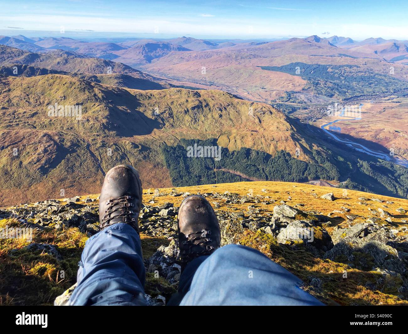 Vista dei piedi degli escursionisti e degli stivali in pelle sulla cima di ben More guardando verso nord-ovest, Crianlarich Scozia - Immagine stock catturata con smartphone