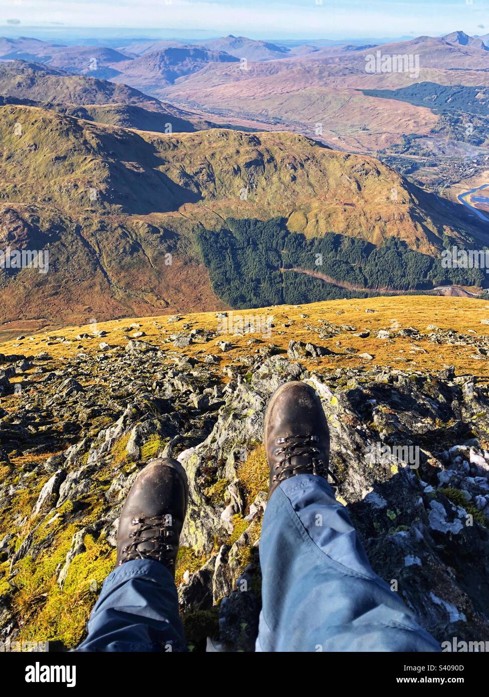 Vista dei piedi degli escursionisti e degli stivali in pelle sulla cima di ben More guardando verso nord-ovest, Crianlarich Scozia - Immagine stock catturata con smartphone
