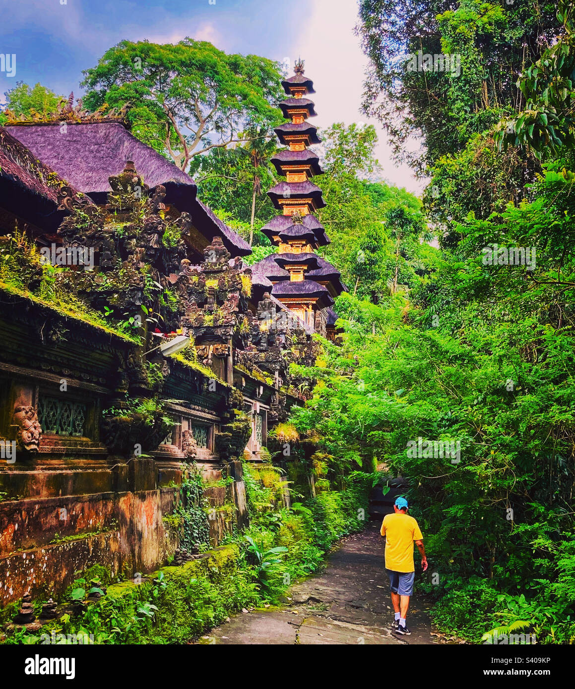 Uomo che cammina davanti ad un tempio a Ubud Bali - Immagine stock catturata con smartphone