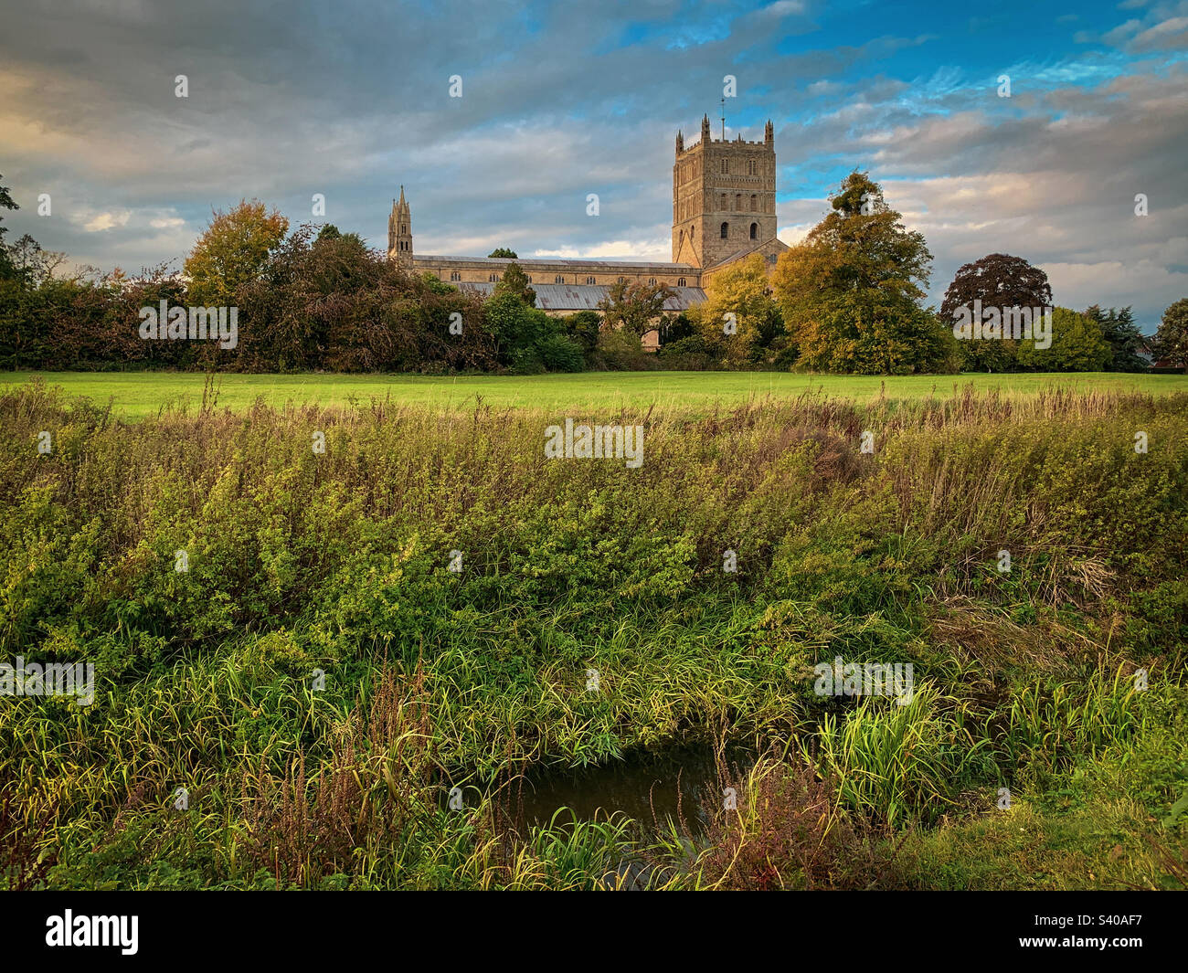 I colori autunnali arrivano all'abbazia di Tewkesbury in un bellissimo pomeriggio di ottobre, nel Gloucestershire, Regno Unito. Una foto di un telefono cellulare con post-elaborazione di un telefono o di un tablet. - Immagine stock catturata con smartphone