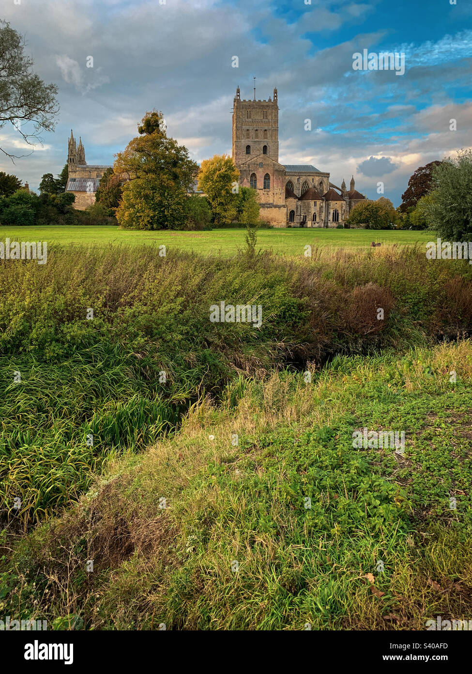 I colori autunnali arrivano all'abbazia di Tewkesbury in un bellissimo pomeriggio di ottobre, nel Gloucestershire, Regno Unito. Una foto di un telefono cellulare con post-elaborazione di un telefono o di un tablet. - Immagine stock catturata con smartphone