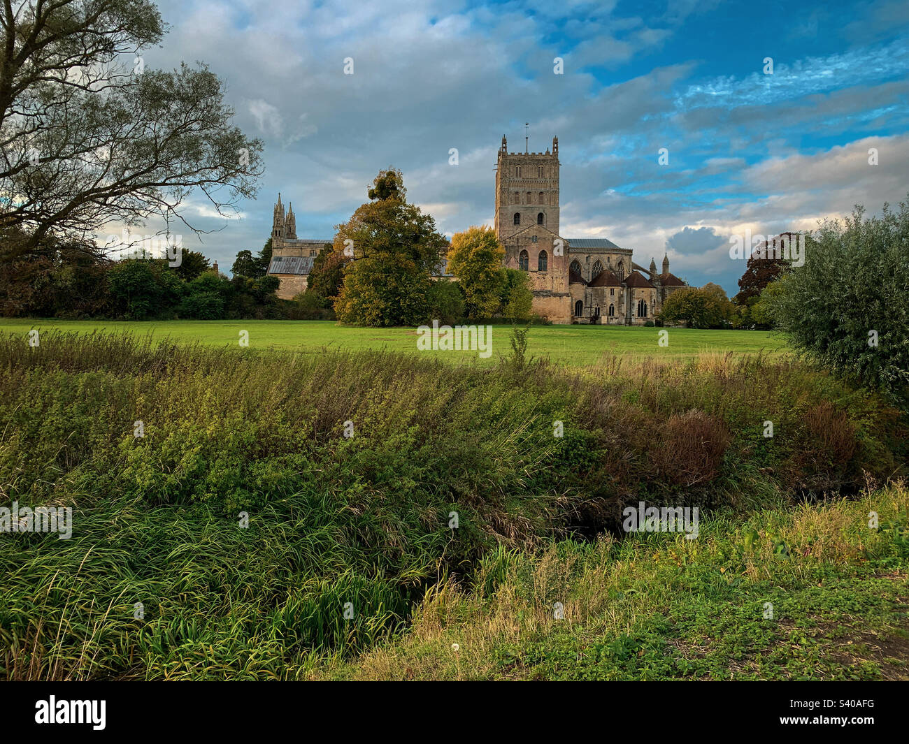 I colori autunnali arrivano all'abbazia di Tewkesbury in un bellissimo pomeriggio di ottobre, nel Gloucestershire, Regno Unito. Una foto di un telefono cellulare con post-elaborazione di un telefono o di un tablet. - Immagine stock catturata con smartphone