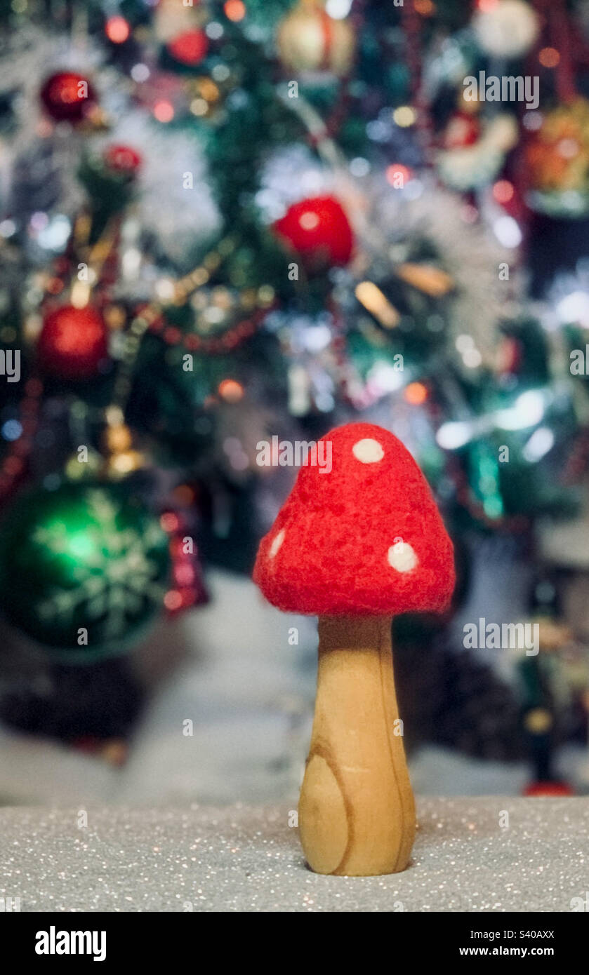 Uno sgabello rosso e bianco fatto di legno e feltro di fronte ad un albero di Natale sfocato Foto Stock
