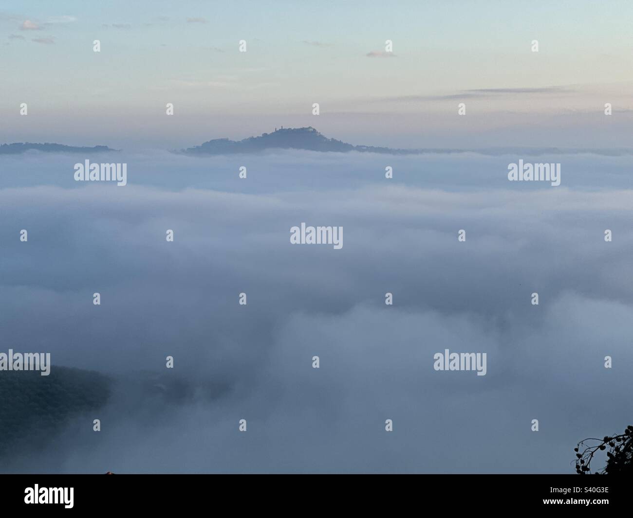 Nebbia nella valle con un villaggio all'orizzonte - Immagine stock catturata con smartphone