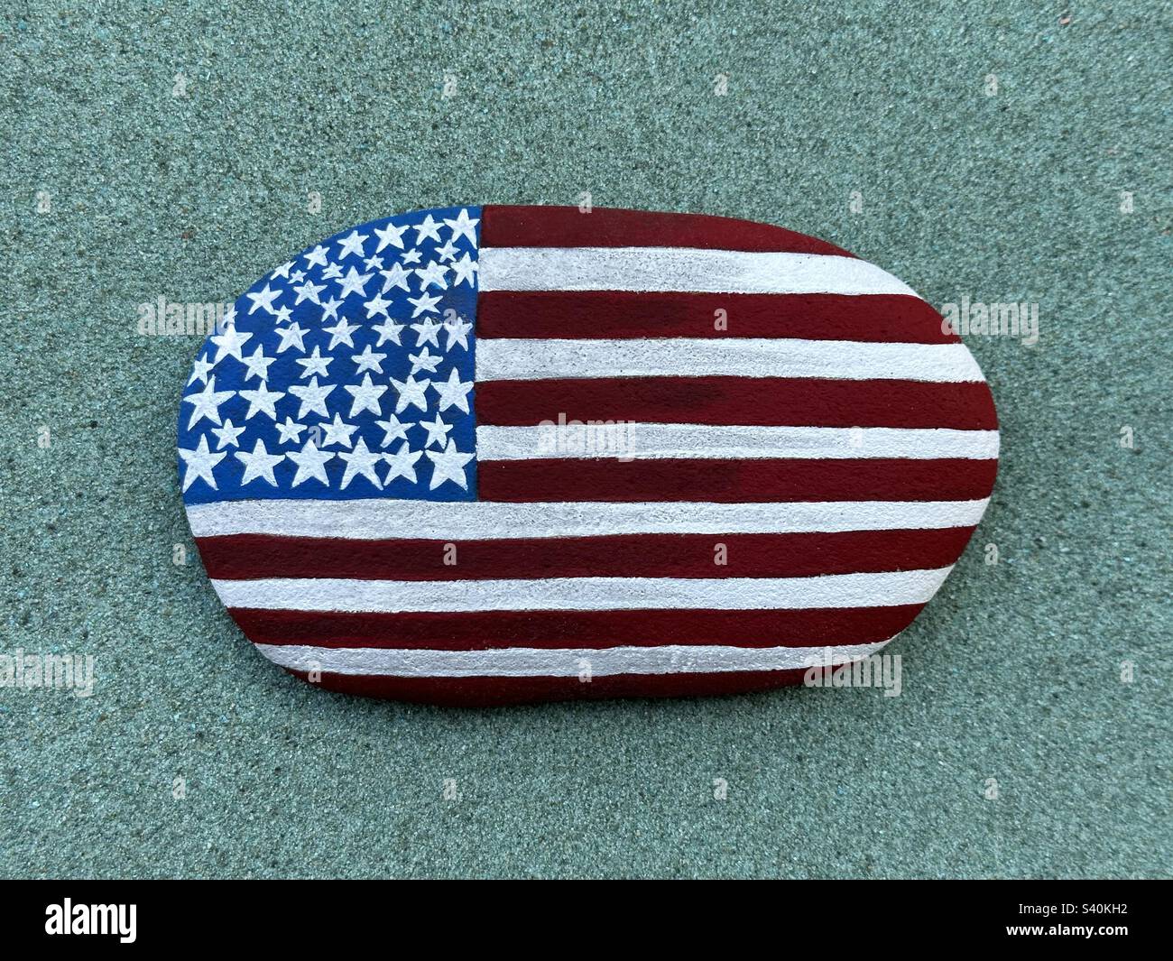 Stati Uniti d'America, bandiera artistica dipinta a mano su una pietra su sabbia verde Foto Stock