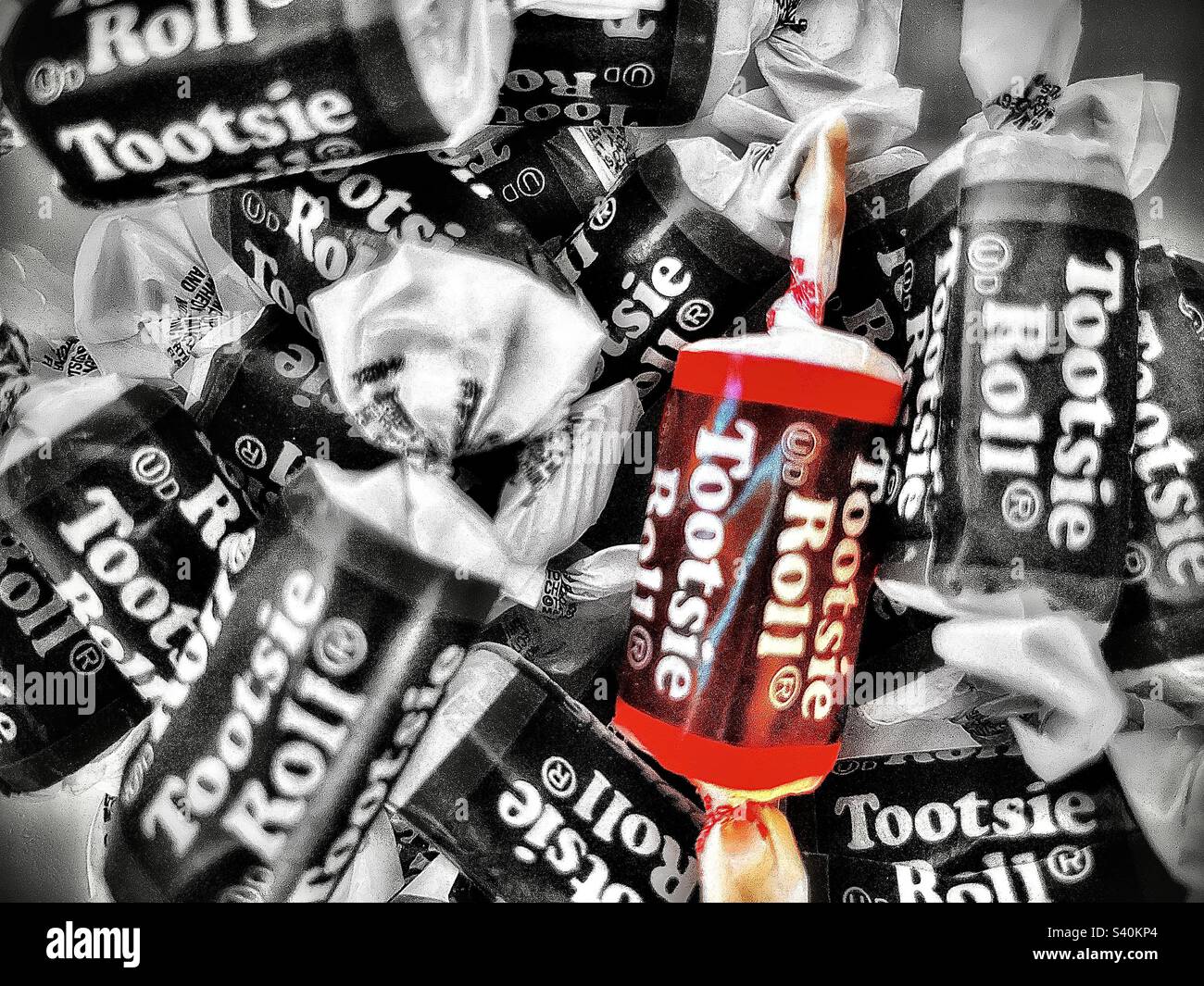 Una ciotola piena di rotoli Tootsie, di medie dimensioni. Un rullo Tootsie è colorato mentre il resto è desaturato. - Immagine stock catturata con smartphone