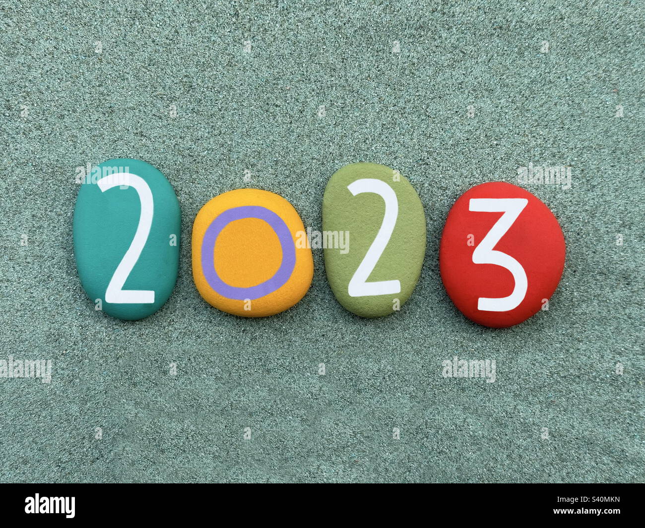 Anno 2023 composto da pietre multicolore dipinte a mano su sabbia verde - Immagine stock catturata con smartphone