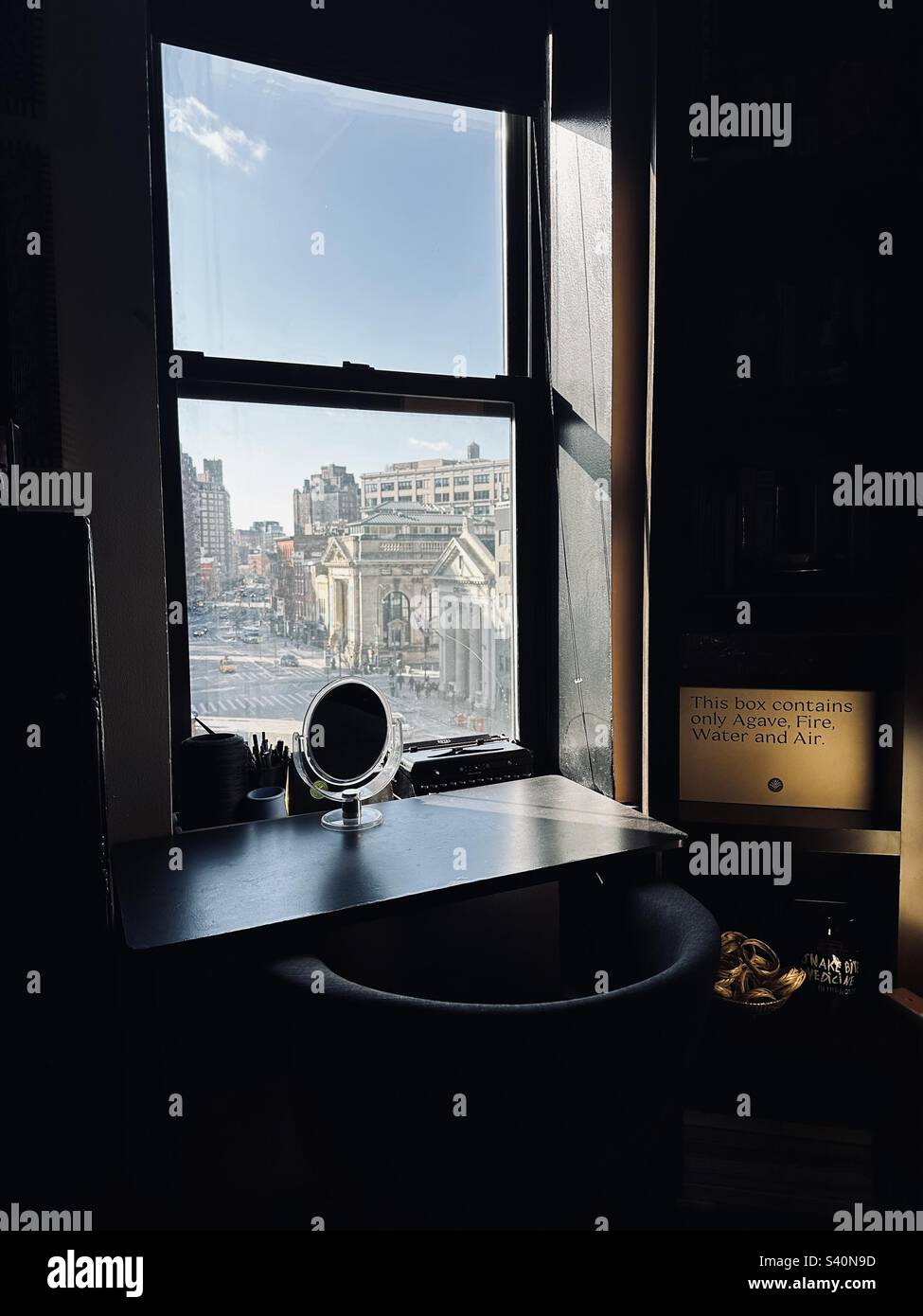 Vista dalla finestra di un appartamento che guarda alla 7th Avenue, Manhattan, New York. Uno specchietto davanti al vetro. Una scatola che dice "questa scatola contiene solo Agave, fuoco, acqua e aria". Per un set di degustazione Mescal Foto Stock