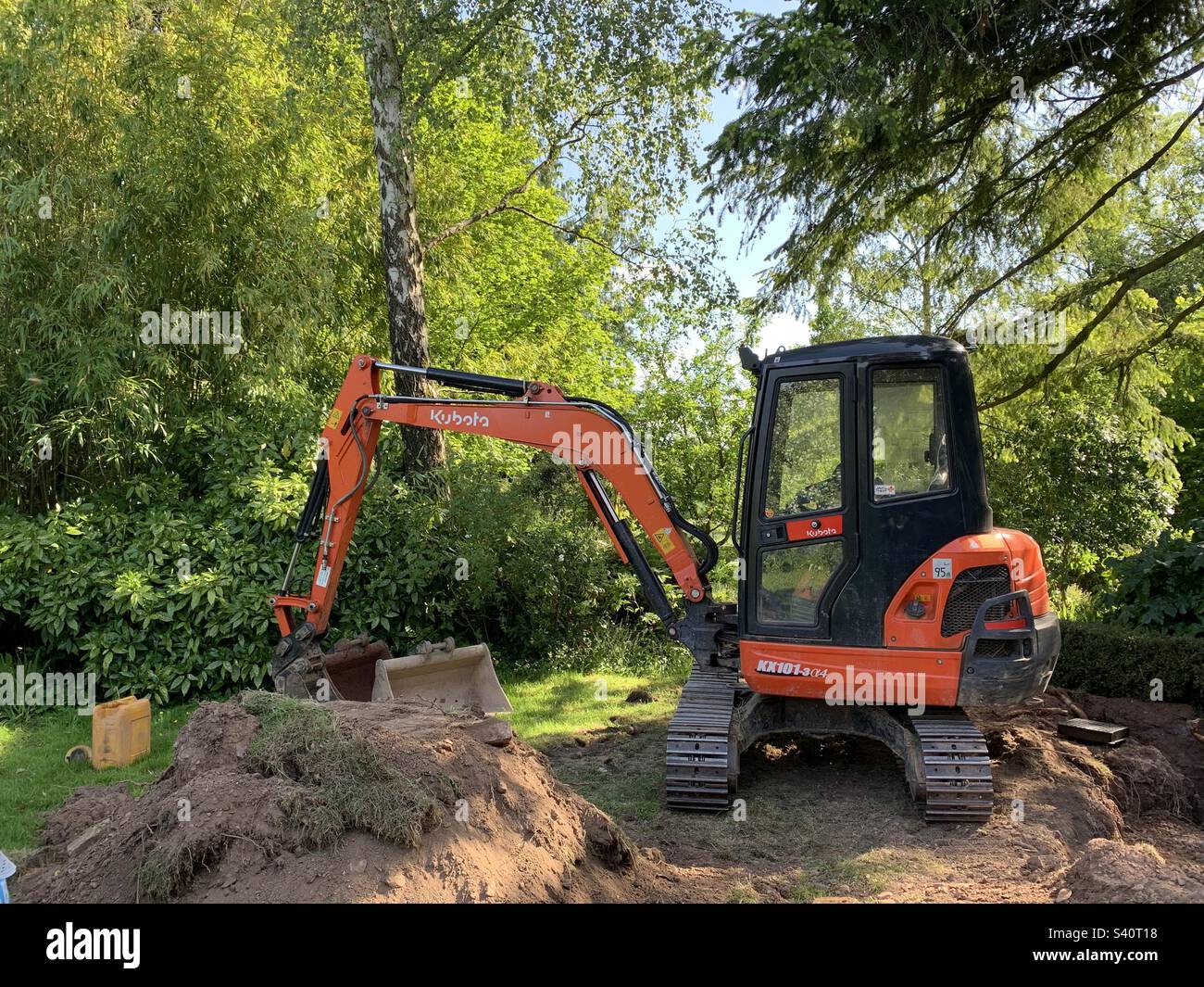 Giardinaggio con trattore scavatore in estate Foto Stock
