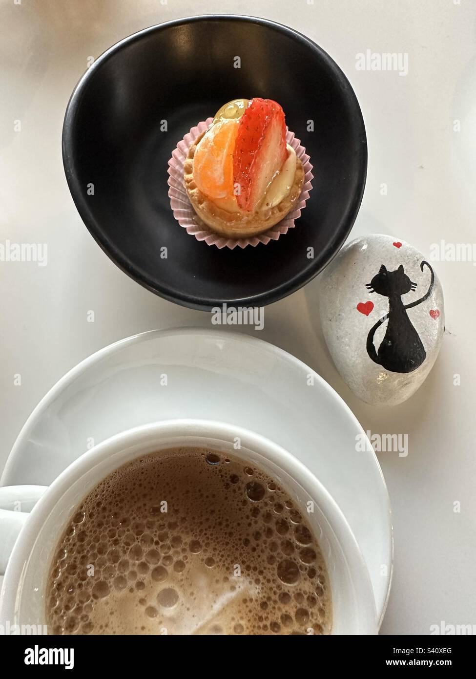 Dessert di frutta con una tazza di caffè e un gatto dipinto su una pietra al bar Foto Stock