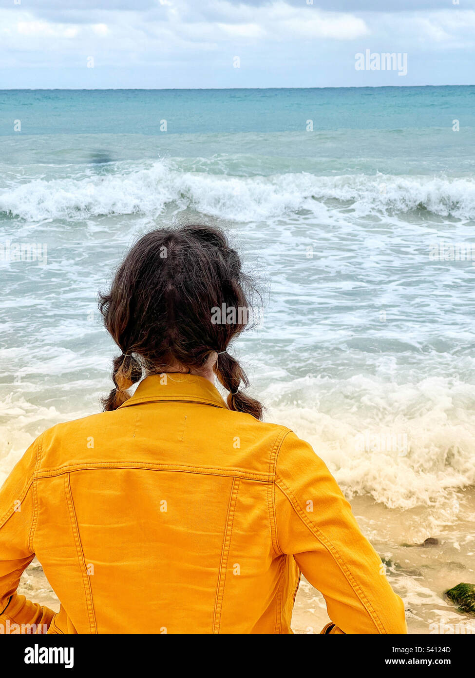 Giovane donna in giacca gialla jean che guarda al Mar dei Caraibi nella Riviera Maya, messico Foto Stock